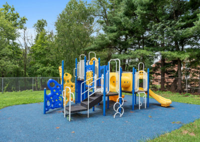 Playground with a blue and yellow jungle gym at Creekside Apartments