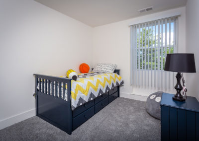 Bedroom with a blue children’s bed, carpet flooring, and a blue nightstand