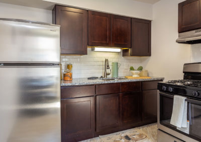 Kitchen area Creekside apartments with brown cabinets and stainless-steel appliances