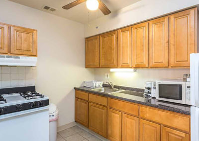 Kitchen area with light brown cabinets and white appliances