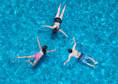 Three friends swimming in a glistening swimming pool
