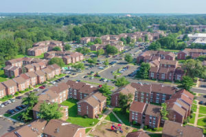 Aerial view of the beautiful Creekside Apartments complex in Bensalem, PA with brown buildings and vast parking spaces
